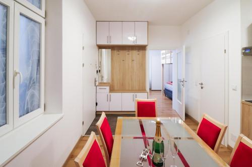 维也纳CozyNite Premium Apartment Schönbrunn 1的厨房以及带玻璃桌和红色椅子的用餐室。