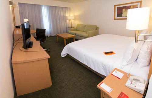 墨西哥城埃卡特佩克嘉年华酒店的酒店客房配有一张床和一张书桌及一台电视