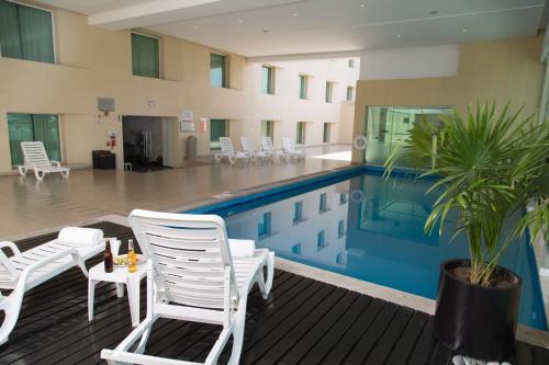 墨西哥城埃卡特佩克嘉年华酒店的一座带白色椅子和棕榈树的游泳池