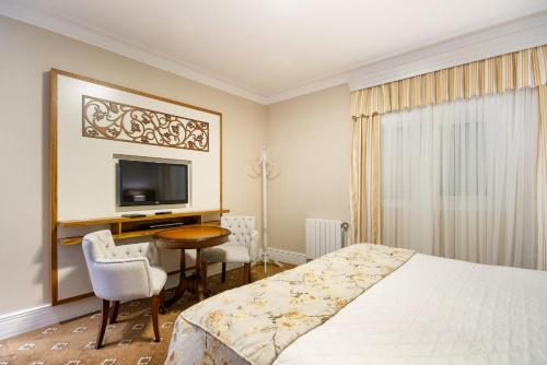 坎波斯杜若尔当波萨达意大利亚埃勒甘扎旅馆的一间卧室配有一张床、一张书桌和一台电视。