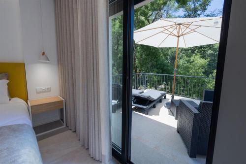 奥利维拉多霍斯比托Be Alva的一间卧室配有一张床,阳台配有遮阳伞