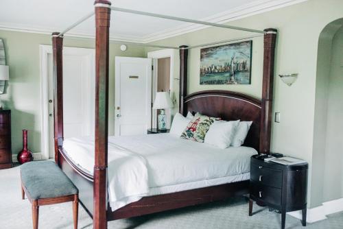 GrotonBenn Conger Inn的一间卧室配有四柱床和椅子