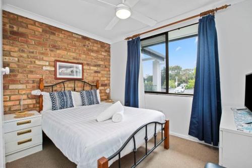 拜伦湾Byron Bay Accom Unit 6 70 Lawson Street - Atlantis的一间卧室设有一张床和砖墙