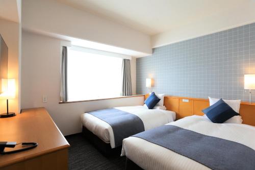 冈山HOTEL MYSTAYS Okayama的酒店客房设有两张床、一张书桌和一个窗户。