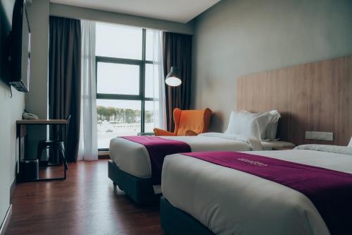 民都鲁Amigo Hotel Bintulu的酒店客房,设有两张床和一张橙色椅子