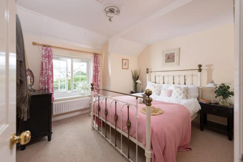 GwithianPump Cottage and Annexe, Gwithian的一间卧室配有一张带粉色毯子的床