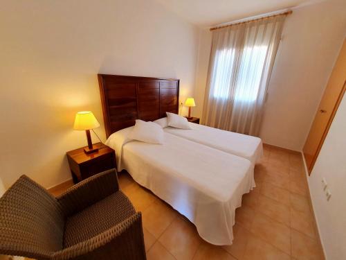 利乌玛Apartamentos Las Dunas-B的卧室配有一张白色大床和一把椅子
