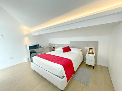 里乔内La Mansardina的白色卧室配有一张带红色毯子的大床