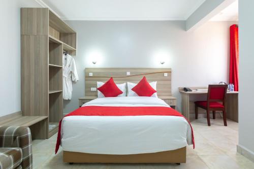 纳库鲁Rock Hyrax Hotel的一间卧室配有一张带红色枕头的床和一张书桌