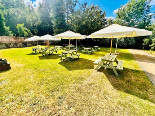 BuckinghamshireGeorge & Dragon Hotel的一组野餐桌和雨伞在草地上