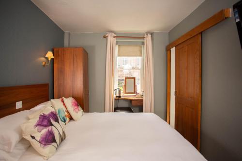 特维德上游的贝里克Queens Head Hotel的卧室配有白色的床和窗户。