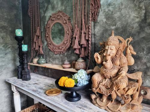 坎古Stay at My Place Bali的坐在桌子上的雕像,放着一碗鲜花