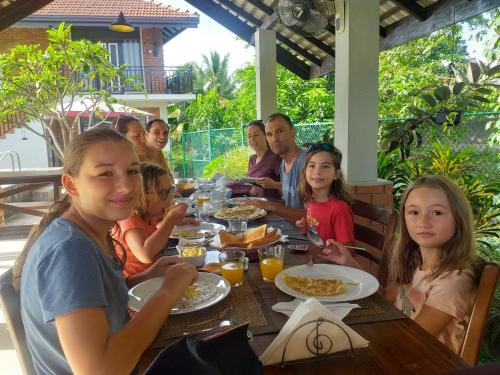 尼甘布内贡博绿树住宿加早餐旅馆的一群坐在餐桌上吃食物的人