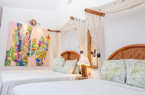 阿卡普尔科Monyoli Hotel & Boutique的卧室设有2张床和白色的墙壁。