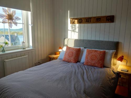 MangerstaHona的一间卧室配有带橙色枕头的床和窗户。