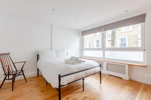 伦敦Spacious 1 Bedroom Apartment in Vibrant Angel的卧室配有床、椅子和窗户。