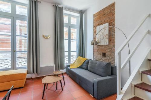 图卢兹Very nice duplex located on the main square - Toulouse - Welkeys的带沙发的客厅和部分窗户。