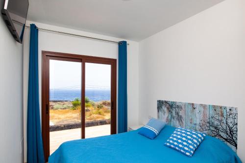 弗龙特拉Casa Tabaiba Dulce的一间配备有蓝色床的卧室,享有海景