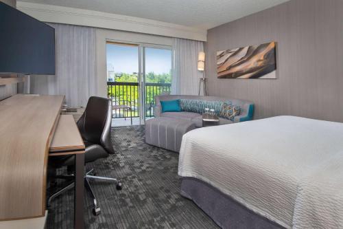 艾伦镇艾伦镇伯利恒利哈伊谷机场万怡酒店的酒店客房配有一张床、一张书桌和一张沙发。