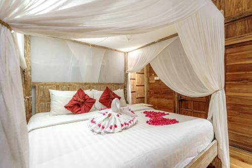 乌鲁瓦图My Dream Bali的一间卧室配有一张带红色鲜花的天蓬床。