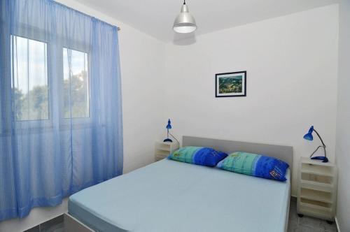 UbliApartments by the sea Pasadur, Lastovo - 8351的一间卧室配有一张带蓝色窗帘的床和一扇窗户