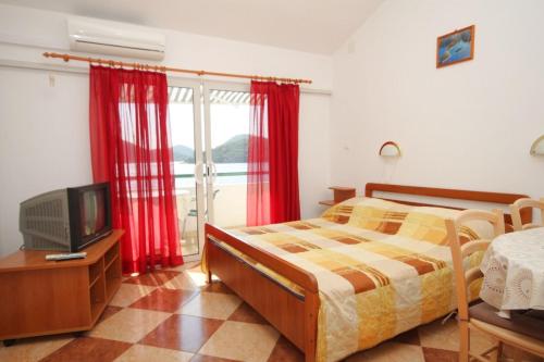 拉斯托伏Apartments by the sea Pasadur, Lastovo - 8391的一间卧室配有床、电视和红色窗帘