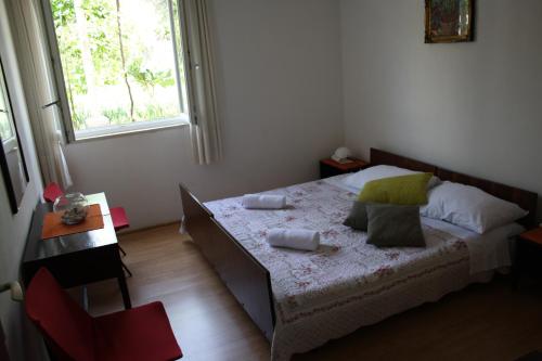 特斯特诺Apartments with a parking space Brsecine, Dubrovnik - 8549的一间卧室配有一张床、一张桌子和一个窗户。