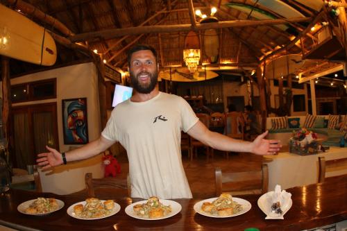 MiramarSirena Surf Lodge Miramar Nicaragua的站在餐桌前,有盘子的食物的人