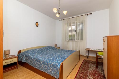 苏佩塔尔Apartment Supetar 11278a的一间卧室配有一张床、一张桌子和一个窗户。
