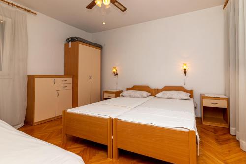 苏佩塔尔Apartments with a parking space Supetar, Brac - 11278的一间卧室配有两张床和吊扇