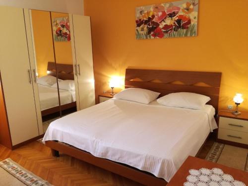 特罗吉尔Apartments by the sea Arbanija, Ciovo - 11321的卧室配有白色的床和镜子