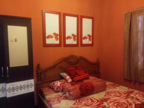 塔旺曼谷Argolawu Homestay的卧室内的一张床铺,墙上挂着四张照片