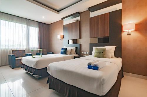 万隆Urbanview Hotel Newton Riau Bandung by RedDoorz的酒店客房,配有两张床和椅子