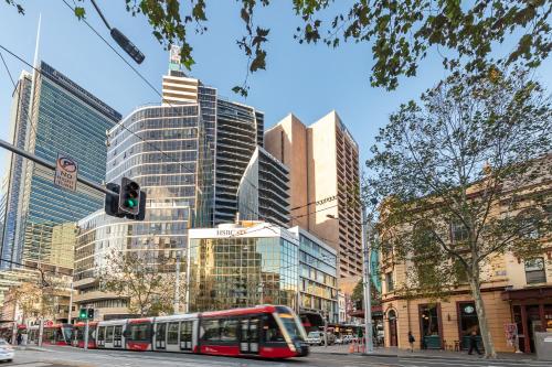 悉尼Meriton Suites Campbell Street, Sydney的一条城市街道,在高楼前有一辆公共汽车