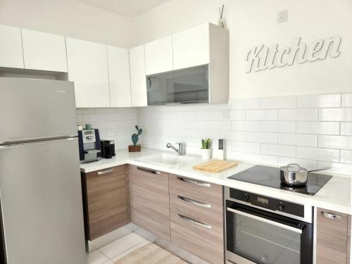 埃拉特Melony Apartments Yam Suf Street的厨房配有白色橱柜和不锈钢冰箱