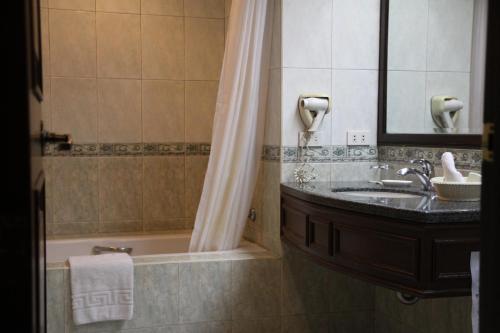 马尼拉Herald Suites Solana的一间带水槽、浴缸和镜子的浴室