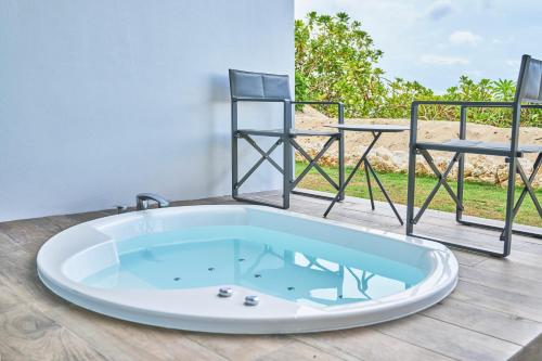 宫古岛Watermark Hotel & Resorts Okinawa Miyakojima的浴缸(铺有木地板,配有两把椅子)