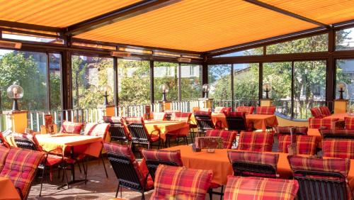 因斯布鲁克阿尔皮纳咖啡酒店的一间设有桌椅的餐厅,位于带窗户的房间内