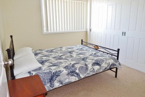 西南岩Village Centre 3 South West Rocks的一间卧室配有一张带蓝白色毯子的床