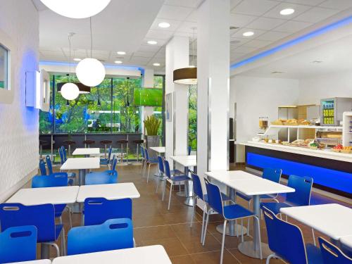 华沙ibis budget Warszawa Reduta的一间设有白色桌子和蓝色椅子的自助餐厅