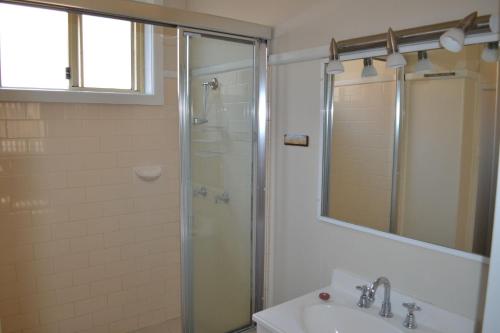 西南岩Clarkes Flat 1的带淋浴、盥洗盆和镜子的浴室