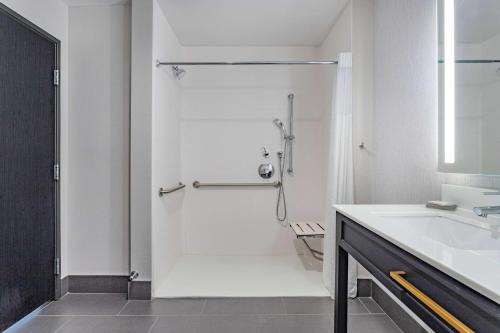 南本德La Quinta Inn & Suites by Wyndham South Bend near Notre Dame的带淋浴和盥洗盆的白色浴室