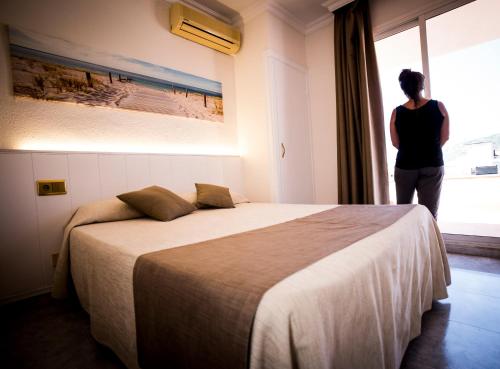 普拉加德阿罗克莱默尔酒店的站在卧室里,看着窗外的女人