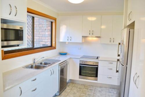西南岩Seaview Townhouse 3的白色的厨房配有水槽和冰箱