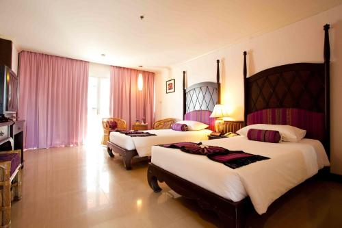 七岩美塔法来度假酒店的两张位于酒店客房的床,配有粉红色窗帘