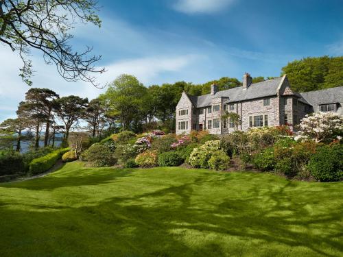 基洛格林Ard na Sidhe Country House Hotel的一座带郁郁葱葱的绿色庭院的大房子
