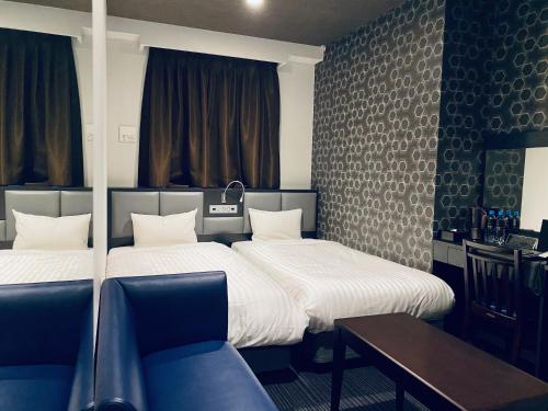 福冈福冈博多弗拉顿酒店的客房设有两张床、一张桌子和一张沙发。