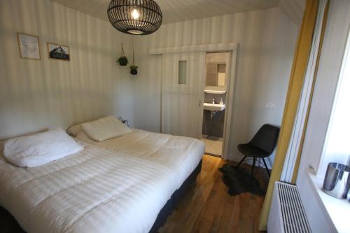 圣尼古拉斯哈Recreatieappartement BoerdeRijlst - De Winkel的一间卧室配有一张床和一把椅子
