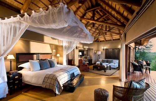 斯库库扎Lion Sands - Tinga Lodge的一间卧室设有一张床和一间客厅。