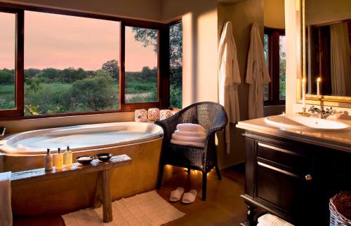 斯库库扎Lion Sands - Tinga Lodge的带浴缸和盥洗盆的大浴室